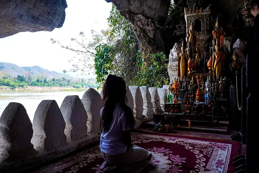 A student observing a shrine inside a cave in Laos